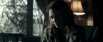 Movie still from “The Veil” (2016), directed by Phil Joanou – A young woman sitting in front of a window looking down; Close Up shot, Over the shoulder angle
