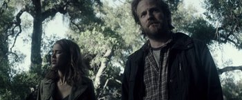 Movie still from “The Veil” (2016), directed by Phil Joanou – A man and a woman standing next to each other in front of a tree; Medium shot, Low angle