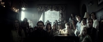 Movie still from “The Veil” (2016), directed by Phil Joanou – A group of people sitting around a table with lit candles; Wide shot, Over the shoulder angle