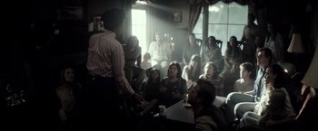 Movie still from “The Veil” (2016), directed by Phil Joanou – A group of people sitting in a room; Wide shot, Over the shoulder angle