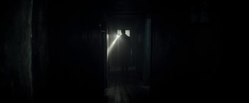 Movie still from “The Veil” (2016), directed by Phil Joanou – A man standing in a dark room in front of a window; Wide shot, Low angle