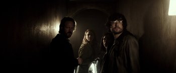 Movie still from “The Veil” (2016), directed by Phil Joanou – A group of people standing next to each other in a dark room; Medium shot, Low angle