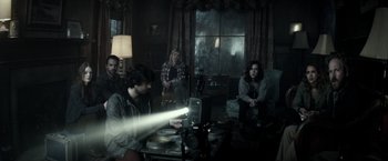 Movie still from “The Veil” (2016), directed by Phil Joanou – A group of people sitting around a living room; Wide shot, High angle