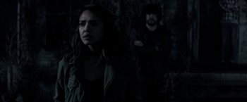 Movie still from “The Veil” (2016), directed by Phil Joanou – A woman standing next to a man in a dark room; Medium shot, Over the shoulder angle