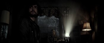 Movie still from “The Veil” (2016), directed by Phil Joanou – A man and a woman are sitting in a dark room; Medium shot, Low angle