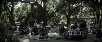 Movie still from “The Veil” (2016), directed by Phil Joanou – A group of people sitting on a blanket in the woods; Wide shot, High angle