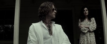 Movie still from “The Veil” (2016), directed by Phil Joanou – A man with long brown hair wearing a white shirt; Close Up shot, Low angle