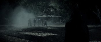 Movie still from “The Veil” (2016), directed by Phil Joanou – A group of people standing in the dark; Wide shot, Over the shoulder angle