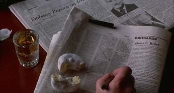 Movie still from “The Verdict” (1982), directed by Sidney Lumet – A hand is writing on a newspaper with a piece of food on top of it; Extreme Close Up shot, Overhead angle