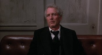 Movie still from “The Verdict” (1982), directed by Sidney Lumet – An older man wearing a suit and tie sitting on a couch; Close Up shot, Low angle