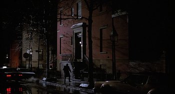 Movie still from “The Verdict” (1982), directed by Sidney Lumet – A person standing on a sidewalk in front of a building at night; Extreme Wide shot, High angle