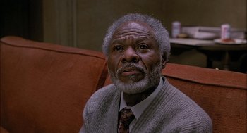 Movie still from “The Verdict” (1982), directed by Sidney Lumet – An older man sitting on a red couch looking into the distance; Close Up shot, High angle