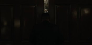 Movie still from “House of Cards” (2013), created by Beau Willimon – A man standing in front of a window in a dark room; Medium shot, Over the shoulder angle