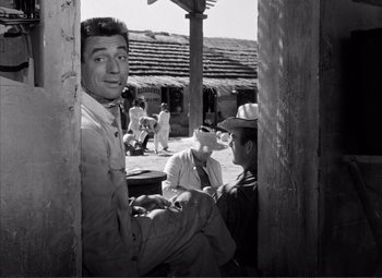 Movie still from “The Wages of Fear” (1953), directed by Henri-Georges Clouzot – A black - and - white photo of men sitting on a porch; Medium shot, Low angle