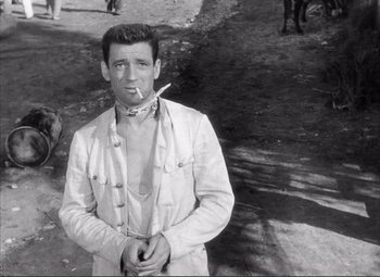 Movie still from “The Wages of Fear” (1953), directed by Henri-Georges Clouzot – A black and white photo of a man smoking a cigarette; Medium shot, Over the shoulder angle