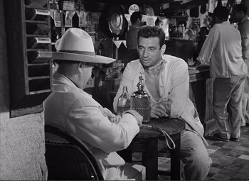 Movie still from “The Wages of Fear” (1953), directed by Henri-Georges Clouzot – Two men are sitting at a table in a store; Medium shot, High angle