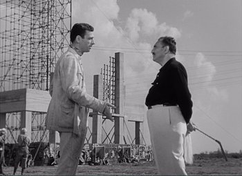 Movie still from “The Wages of Fear” (1953), directed by Henri-Georges Clouzot – Two men shaking hands in a field with power lines in the background; Medium shot, Low angle