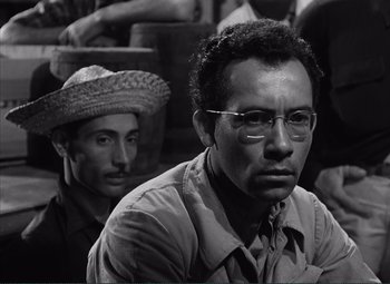 Movie still from “The Wages of Fear” (1953), directed by Henri-Georges Clouzot – A man with glasses and a hat sitting next to another man; Close Up shot, Low angle
