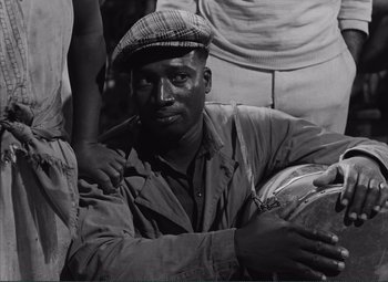 Movie still from “The Wages of Fear” (1953), directed by Henri-Georges Clouzot – An old black and white photo of a man smoking a pipe; Close Up shot, High angle