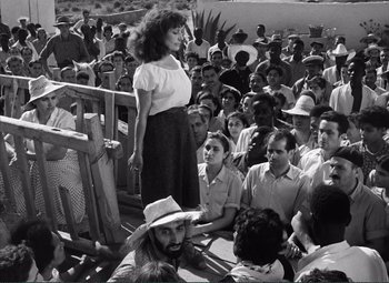 Movie still from “The Wages of Fear” (1953), directed by Henri-Georges Clouzot – A woman standing in front of a group of people; Medium shot, High angle