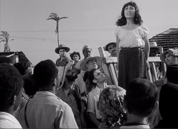 Movie still from “The Wages of Fear” (1953), directed by Henri-Georges Clouzot – A woman standing in front of a group of people; Wide shot, Low angle