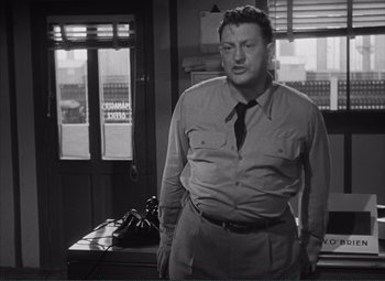 Movie still from “The Wages of Fear” (1953), directed by Henri-Georges Clouzot – A man standing in front of an open door; Medium shot, Low angle