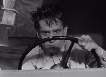 Movie still from “The Wages of Fear” (1953), directed by Henri-Georges Clouzot – A black and white photo of a man driving a car; Close Up shot, High angle