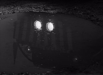 Movie still from “The Wages of Fear” (1953), directed by Henri-Georges Clouzot – A puddle of water with two lights in it; Wide shot, Low angle