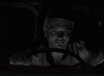 Movie still from “The Wages of Fear” (1953), directed by Henri-Georges Clouzot – A black and white photo of a man driving a car; Close Up shot, Low angle