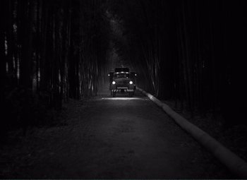Movie still from “The Wages of Fear” (1953), directed by Henri-Georges Clouzot – A car driving down a dark road at night; Extreme Wide shot, High angle