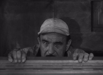 Movie still from “The Wages of Fear” (1953), directed by Henri-Georges Clouzot – An old man with a hat is looking over a railing; Close Up shot, High angle