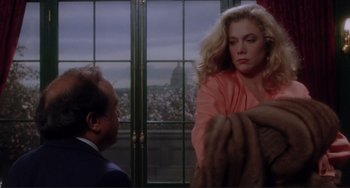 Movie still from “The War of the Roses” (1989), directed by Danny DeVito – A man and a woman standing next to each other in front of a window; Medium shot, Over the shoulder angle