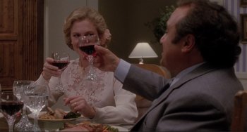 Movie still from “The War of the Roses” (1989), directed by Danny DeVito – A man and a woman sitting at a dinner table drinking red wine; Medium shot, Over the shoulder angle