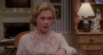 Movie still from “The War of the Roses” (1989), directed by Danny DeVito – An older woman sitting at a dining room table; Close Up shot, Over the shoulder angle