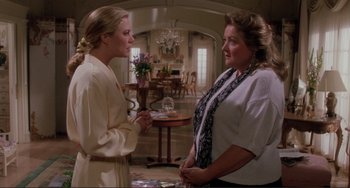Movie still from “The War of the Roses” (1989), directed by Danny DeVito – Two women are talking in a living room; Medium shot, Over the shoulder angle