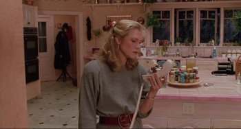 Movie still from “The War of the Roses” (1989), directed by Danny DeVito – A woman is holding a cell phone in her hand; Medium shot, Low angle