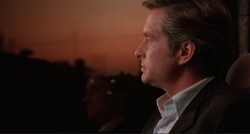 Movie still from “The War of the Roses” (1989), directed by Danny DeVito – A person wearing a suit and tie; Close Up shot, Over the shoulder angle