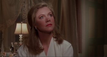 Movie still from “The War of the Roses” (1989), directed by Danny DeVito – A woman in a white shirt looking up at the ceiling; Close Up shot, Over the shoulder angle