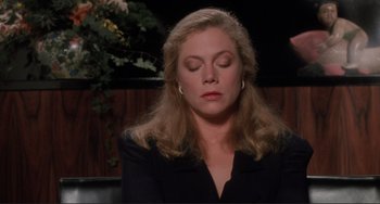 Movie still from “The War of the Roses” (1989), directed by Danny DeVito – A woman with her eyes closed sitting in a room; Close Up shot, High angle
