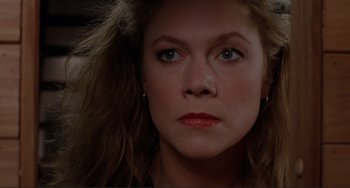 Movie still from “The War of the Roses” (1989), directed by Danny DeVito – A woman's face in a dark room; Close Up shot, Over the shoulder angle