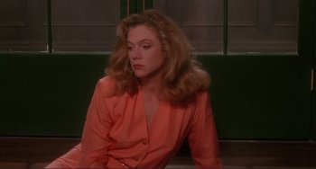 Movie still from “The War of the Roses” (1989), directed by Danny DeVito – A woman sitting down wearing a pink shirt; Medium shot, High angle
