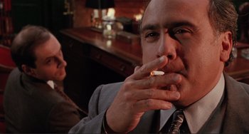 Movie still from “The War of the Roses” (1989), directed by Danny DeVito – A man smoking a cigarette in front of a woman; Close Up shot, Low angle