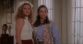 Movie still from “The War of the Roses” (1989), directed by Danny DeVito – Two women standing next to each other in front of a window; Medium shot, High angle