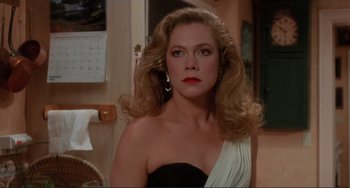 Movie still from “The War of the Roses” (1989), directed by Danny DeVito – A woman with long blonde hair wearing a black and white dress; Close Up shot, Over the shoulder angle