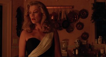 Movie still from “The War of the Roses” (1989), directed by Danny DeVito – A woman in a black and white dress in a kitchen; Medium shot, Low angle