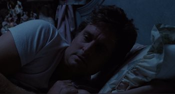 Movie still from “The War of the Roses” (1989), directed by Danny DeVito – A man laying in bed with his head on his pillow; Close Up shot, Over the shoulder angle