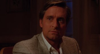 Movie still from “The War of the Roses” (1989), directed by Danny DeVito – A person wearing a suit and tie; Close Up shot, Over the shoulder angle