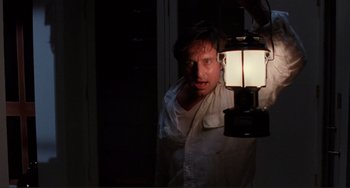 Movie still from “The War of the Roses” (1989), directed by Danny DeVito – A man standing next to an electric lamp; Medium shot, Low angle