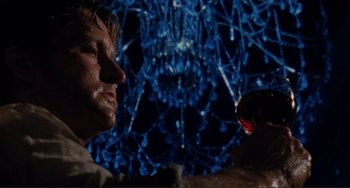 Movie still from “The War of the Roses” (1989), directed by Danny DeVito – A man and a woman looking at each other in front of a blue background; Close Up shot, Low angle