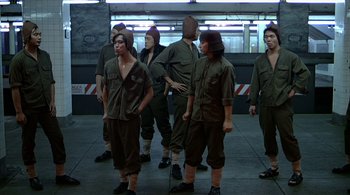 Movie still from “The Warriors” (1979), directed by Walter Hill – A group of people in army fatigues standing in a building; Wide shot, High angle